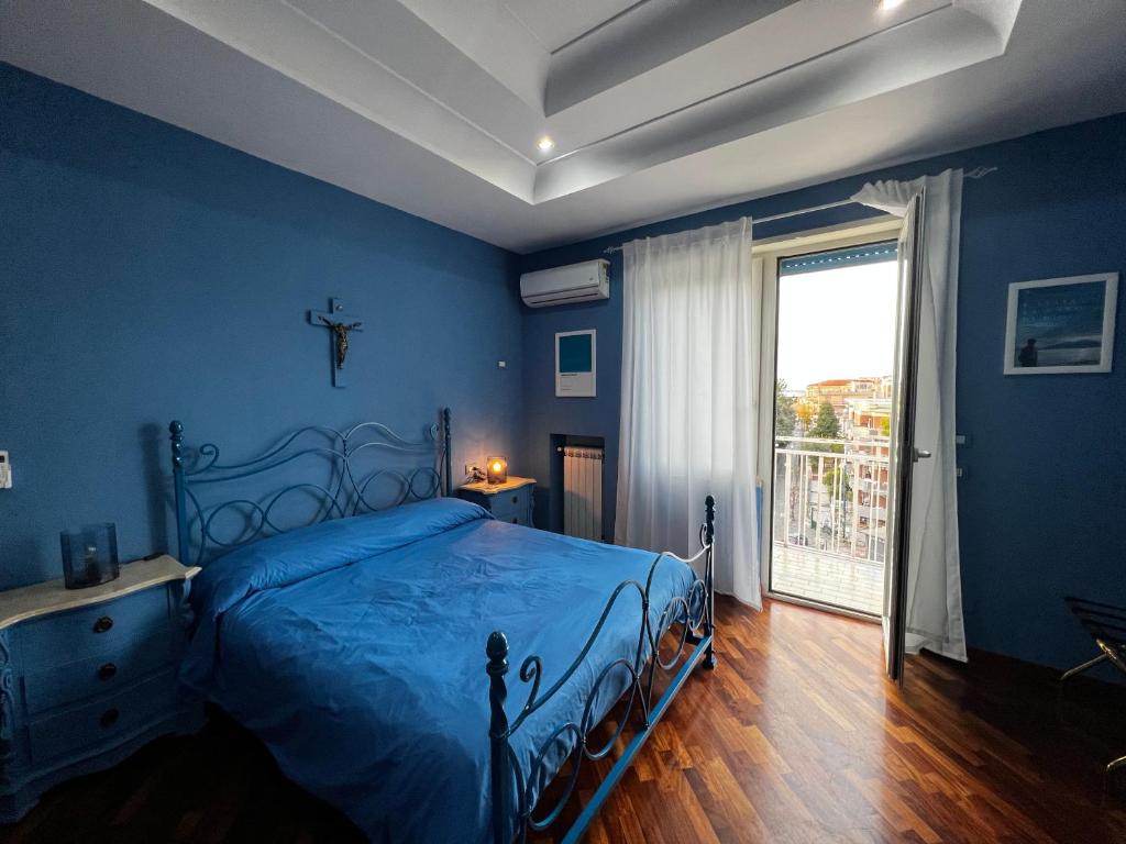 een blauwe slaapkamer met een bed en een groot raam bij RaRoom Colors in Portici