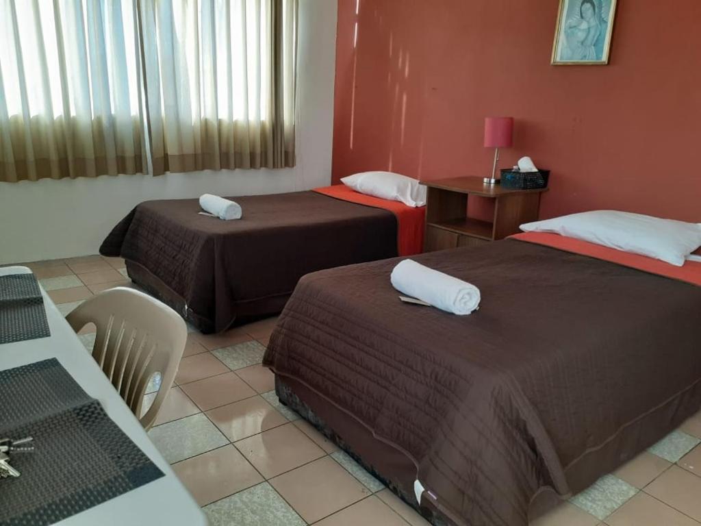 um quarto de hotel com duas camas e uma mesa em HABITACIÓN AZALEA, BAÑO PRIVADO Y COCINETA. em Tepic