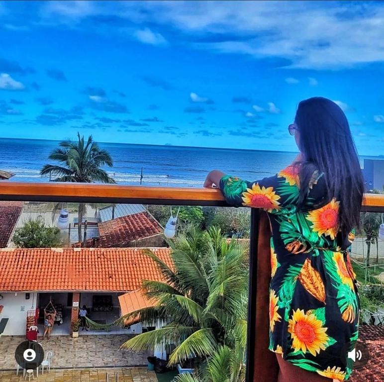 a woman standing on a balcony looking out at the ocean at Hostel Praia Centro Itanhaém in Itanhaém