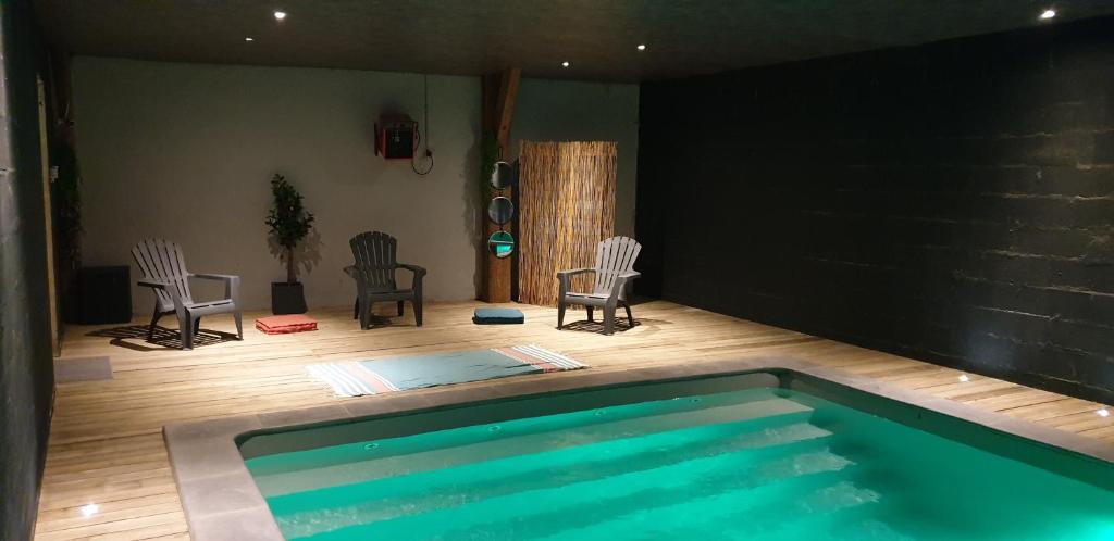 a swimming pool in a room with chairs and tables at Les Colombines in Hombleux