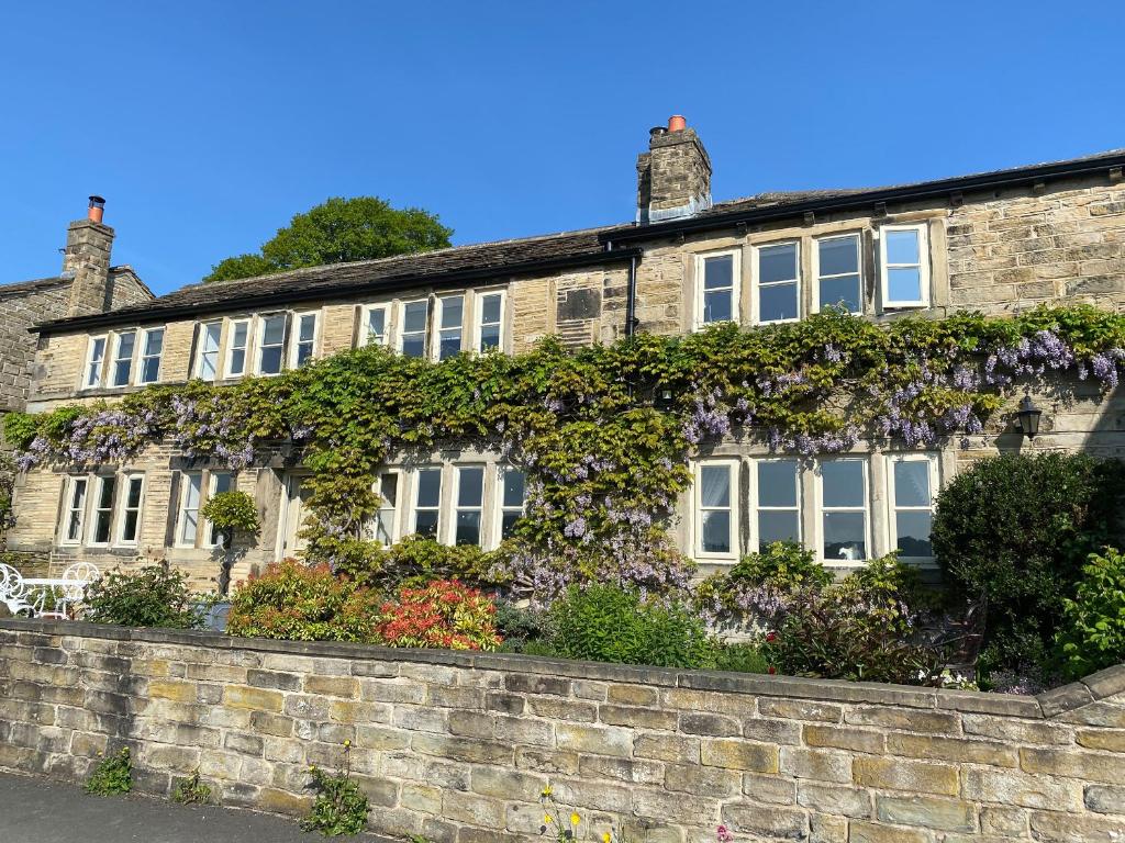 an ivy covered house with flowers on a brick wall at Woodlea Cottage in Huddersfield