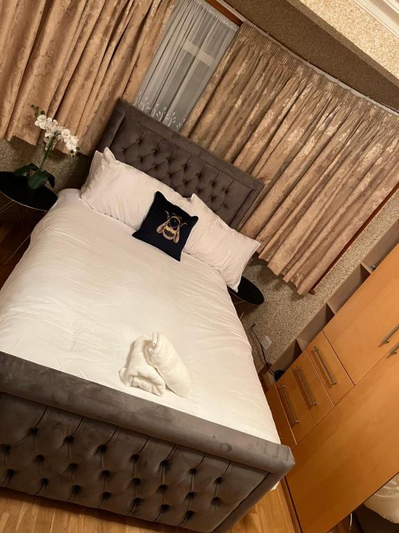 uma cama com uma cabeceira preta e sapatos brancos em TJ Homes - One double bed room with garden view - Next to tube station em Ruislip