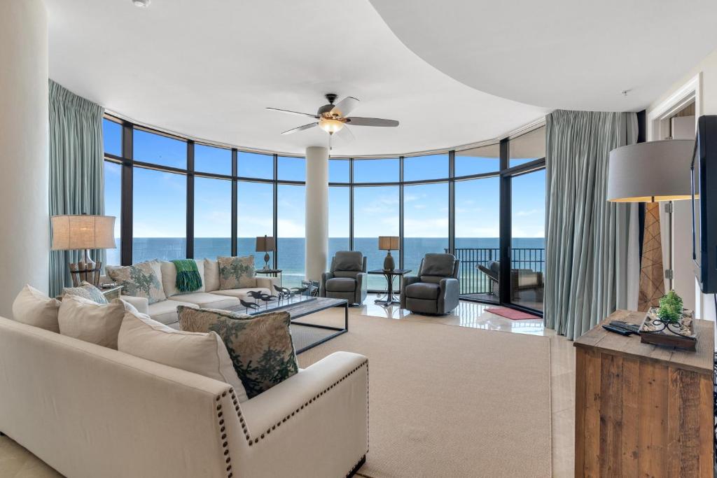 a living room with a couch and chairs and windows at Capri 601 in Perdido Key