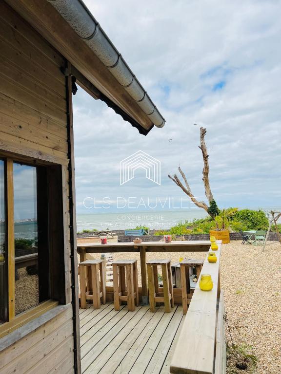 une terrasse en bois avec une table et des chaises sur la plage dans l'établissement Chalet Bord de Mer proche Deauville Le Bois Plage, à Cricquebœuf