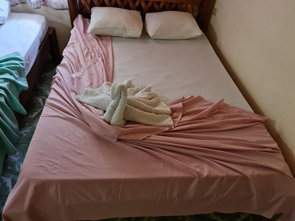 Una cama con sábanas rosas y toallas. en Casa Tucan, en Drake