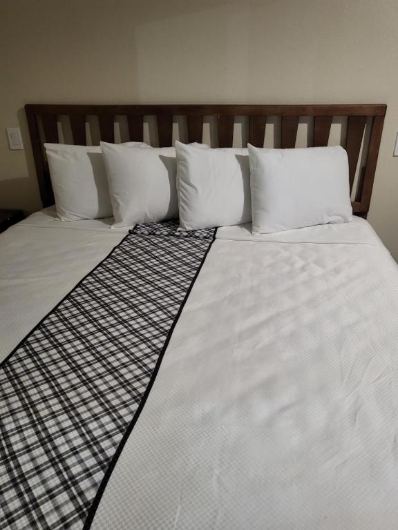 1 cama grande con sábanas y almohadas blancas en Budget Inn, en North Hills
