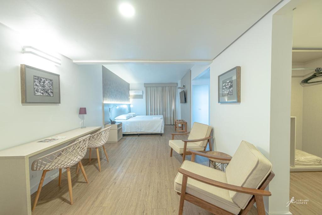 Cette chambre comprend un lit, un bureau et des chaises. dans l'établissement Antonio´s Palace Hotel, à Piracicaba