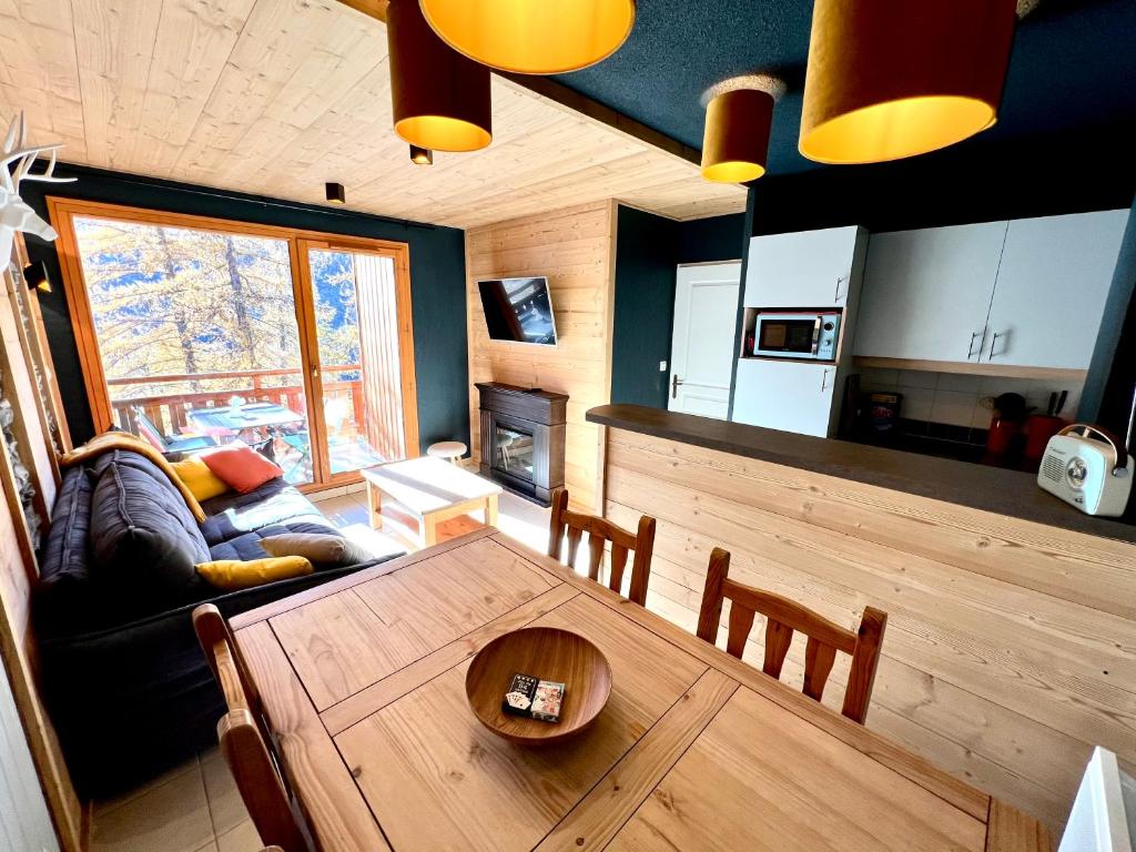 a living room with a wooden table and a kitchen at CENTRE STATION 1800 - Dernier étage Rénové - 2 Chambres 6 personnes - Skis aux pieds in Les Orres