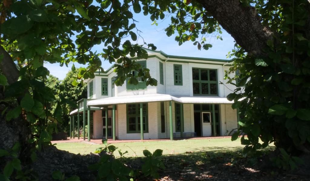 ein großes weißes Haus mit Fenstern und Bäumen in der Unterkunft Oceania House Hotel in Bantam Village