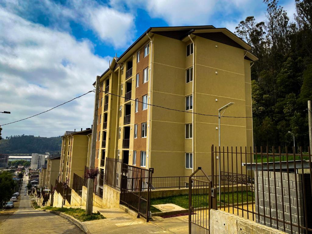 un edificio alto amarillo al lado de una calle en Departamento céntrico con estacionamiento, en Concepción