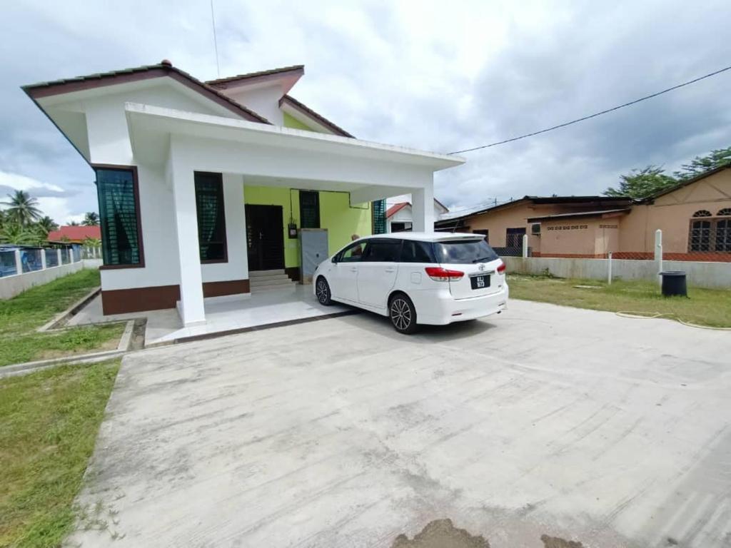 ein weißes Auto, das vor einem kleinen Haus parkt in der Unterkunft Homestay Kemaman Fyna07 Banglo Mewah 5 KM Dari Pantai Kijal in Kijal