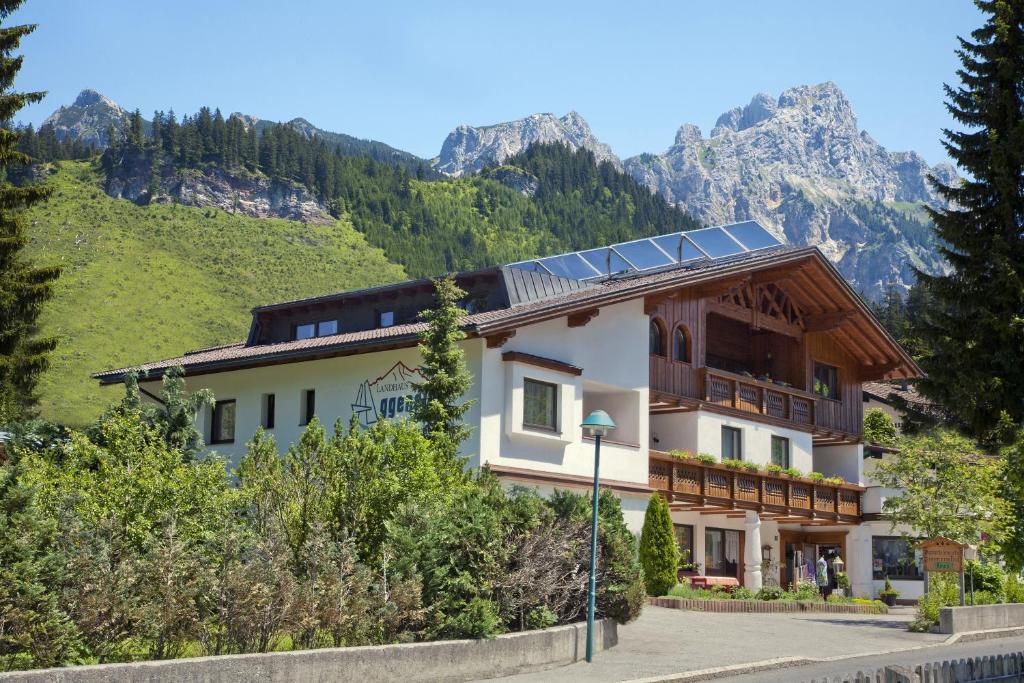 a building with a solar roof with mountains in the background at Landhaus Aggenstein in Haldensee