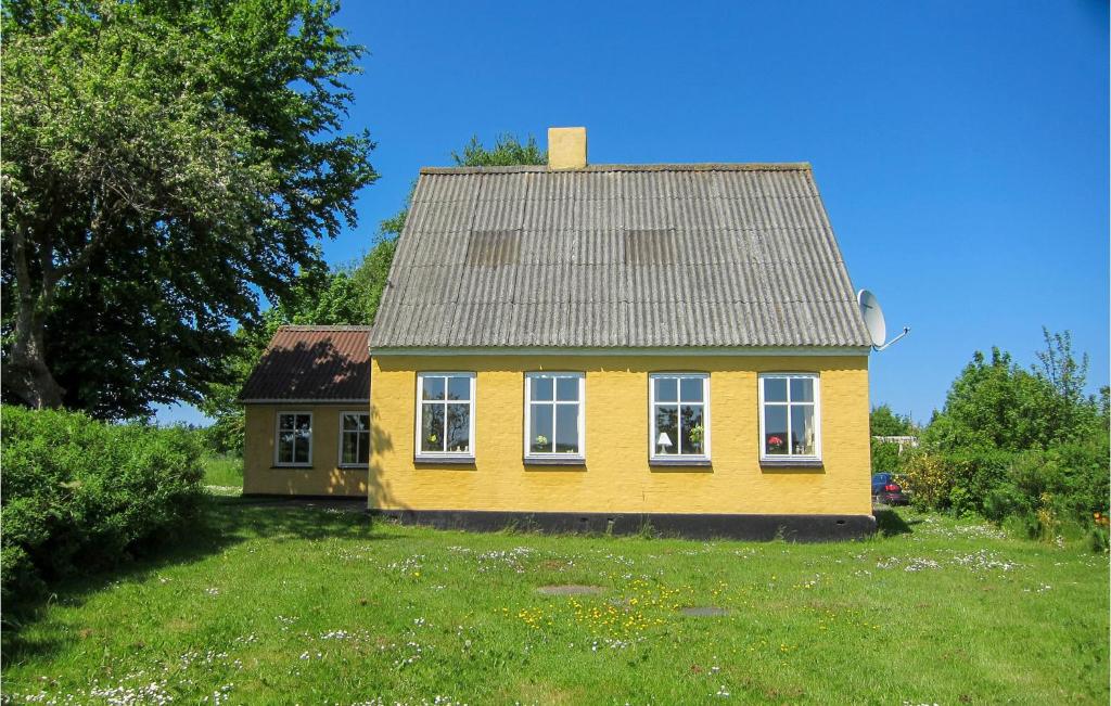 uma casa amarela com um telhado cinzento num quintal em Pet Friendly Home In Gudhjem With Kitchen em Gudhjem