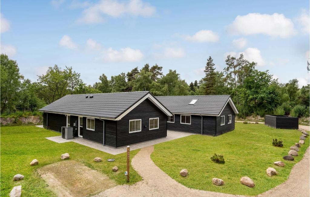 a black house on a grassy field with trees at Stunning Home In Væggerløse With Sauna in Marielyst