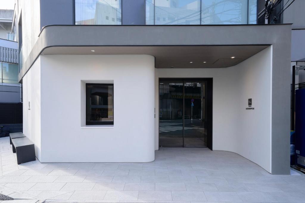 a white building with a revolving door in a city at FAV TOKYO Nishinippori in Tokyo