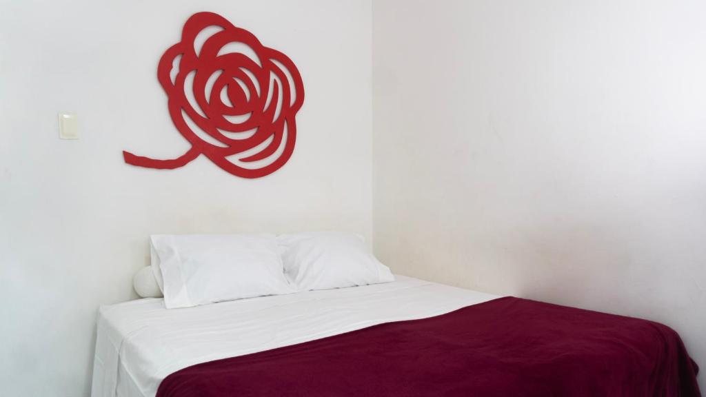 Una cama blanca con un símbolo rojo en la pared en Studio Copacabana Ipanema, en Río de Janeiro
