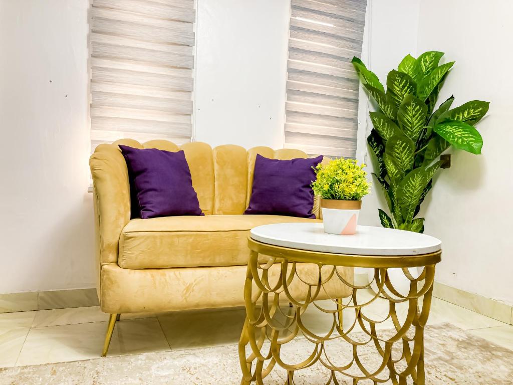 un canapé jaune avec des oreillers violets et une table dans l'établissement ALEXANDRIA COURT, à Lekki