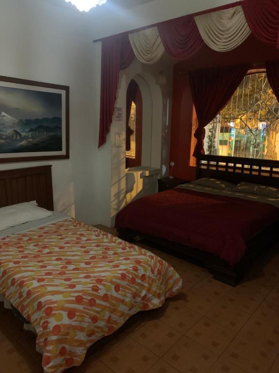 1 dormitorio con 2 camas y ventana en Hostal THE IMPERIAL, en Quito