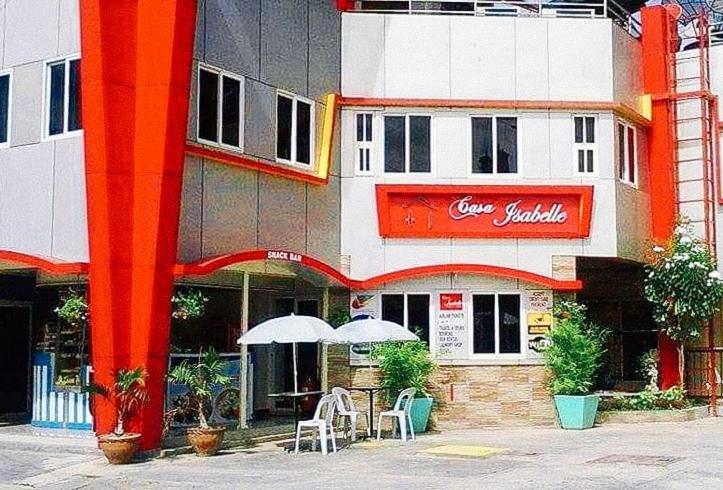 Hinatuan的住宿－RedDoorz @ Isabelle Tourist Hotel Hinatuan，前面有桌子和伞的建筑