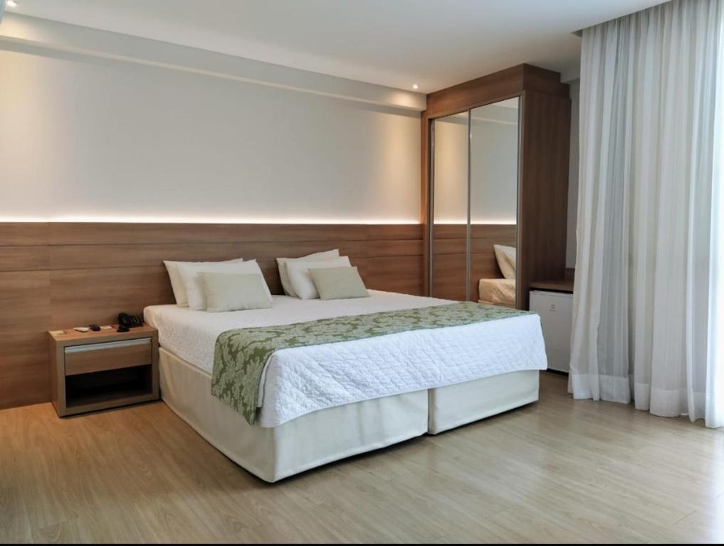 1 dormitorio con 1 cama blanca grande y espejo en Hotel Apart Pedra Azul - Aracê - Domingos Martins, en Domingos Martins