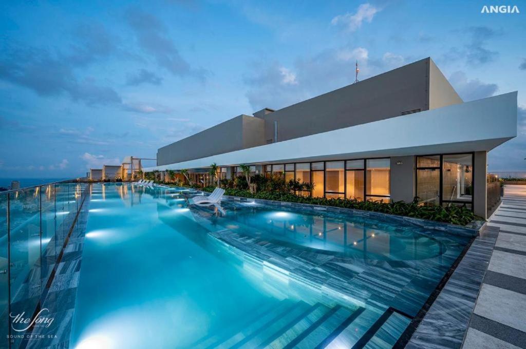 a swimming pool in front of a building at Erica's House - The Sóng Vũng Tàu Condotel Căn hộ biển 5 sao hồ bơi vô cực - The Song Vung Tau Condotel 5-star beach view apartment with infinity pool in Vung Tau