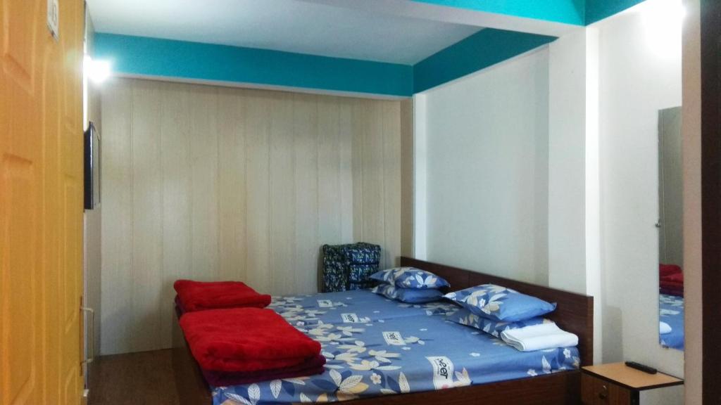 um pequeno quarto com uma cama com uma almofada vermelha em Sunshraya Homestay em Darjeeling