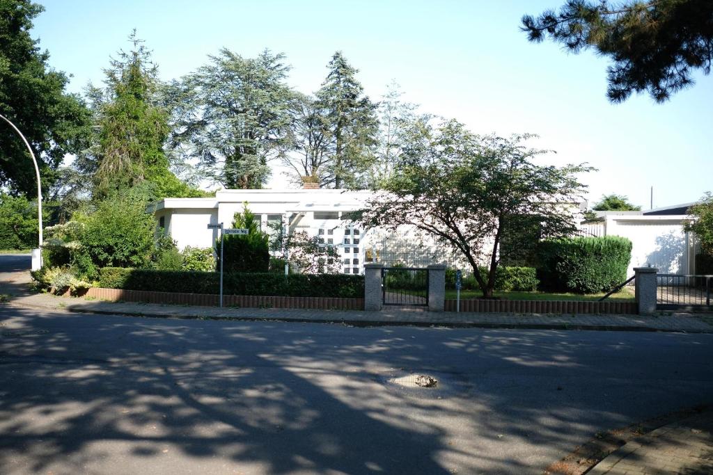 ein weißes Haus mit einem Zaun vor einer Straße in der Unterkunft Ruhiges Haus mit privatem Garten in Halstenbek