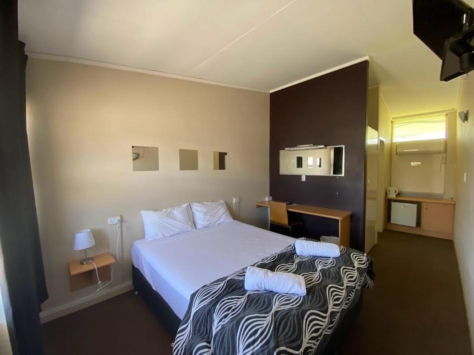 a hotel room with a bed with two pillows on it at Coal n Cattle Hotel Motel in Moura