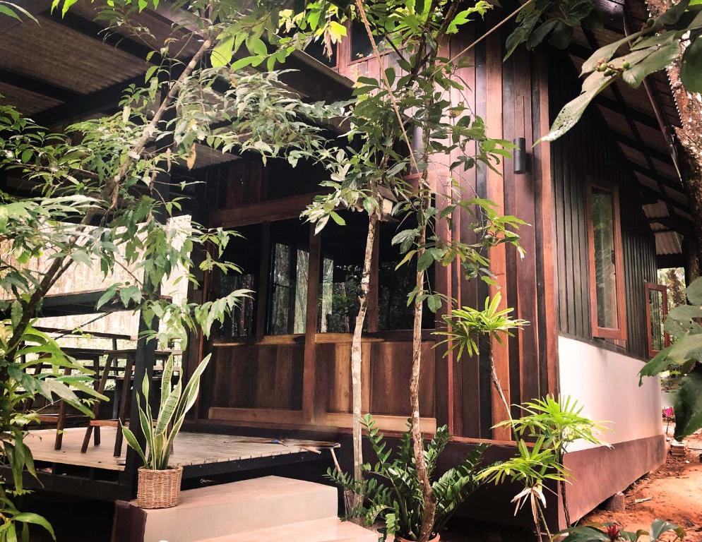 a wooden porch of a house with trees and plants at Luboa Hut - Tiny House in Ko Jum