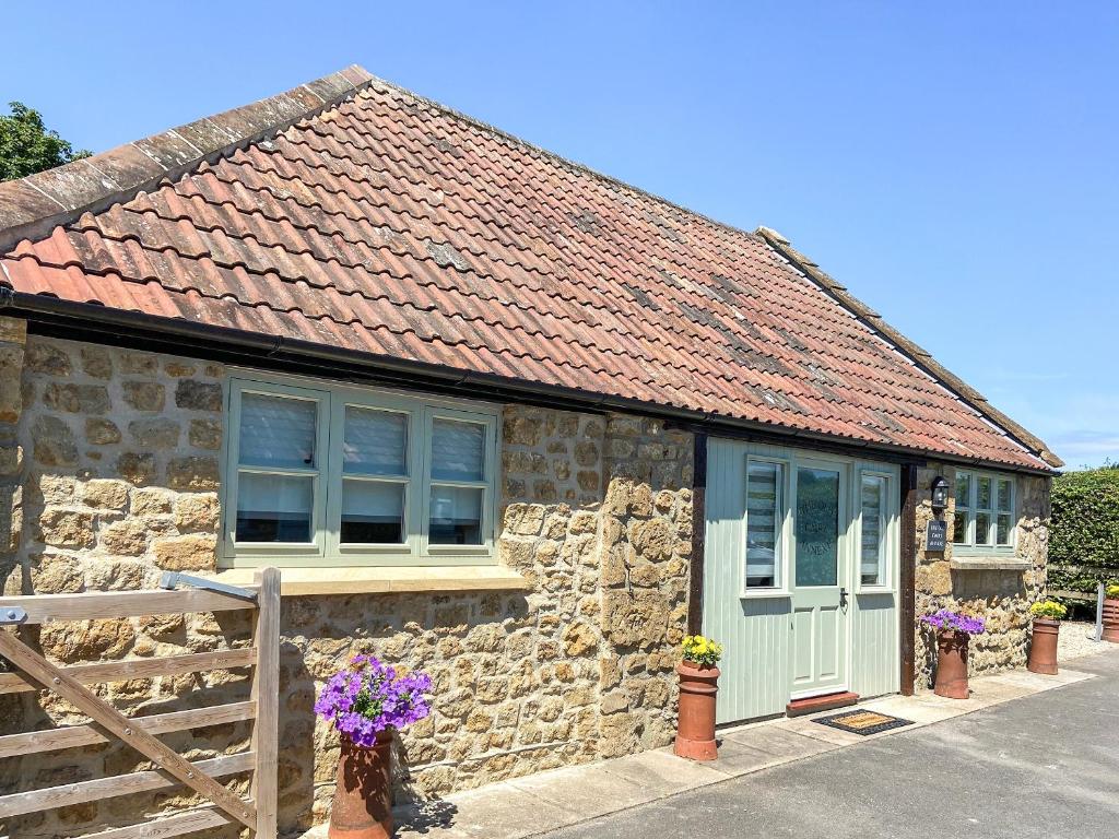 a stone cottage with a white door and windows at The Old Dairy Annexe in Donyatt