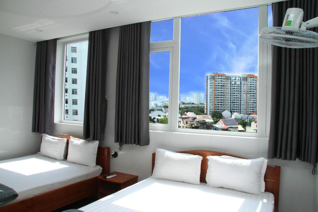 een hotelkamer met 2 bedden en 2 ramen bij HOTEL NGUYEN ANH in Ho Chi Minh-stad