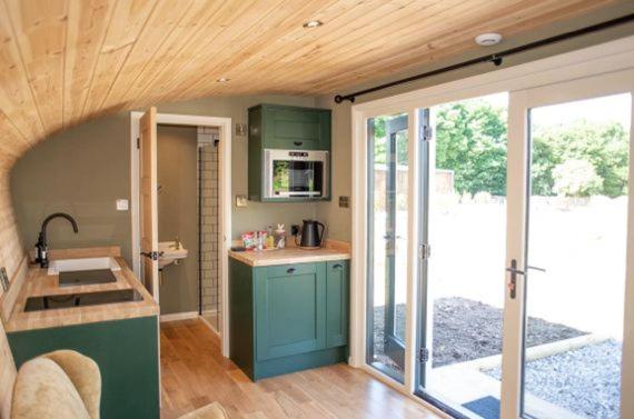 a kitchen with green cabinets and a large sliding glass door at Hares Retreat - Middle Cabin in Foolow