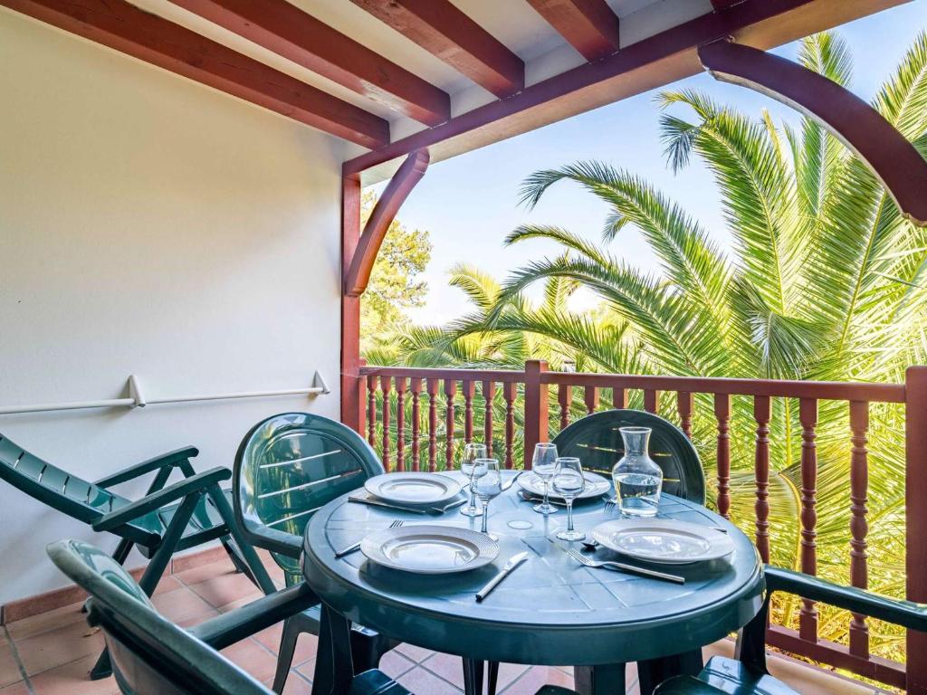 a table with chairs on a balcony with palm trees at Appartement Ciboure, 2 pièces, 4 personnes - FR-1-4-480 in Ciboure