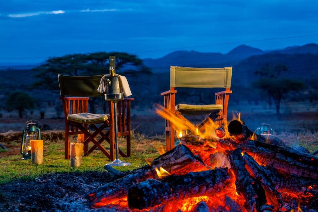two chairs sitting next to a fire and two chairsitures at Kilaguni Serena Safari Lodge in Tsavo