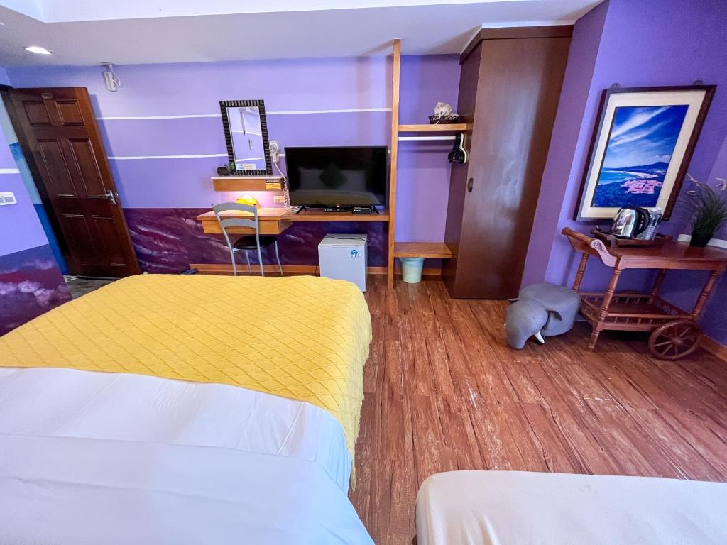 a bedroom with a bed and a desk with a tv at Tz Shin Resort Hostel in Kenting
