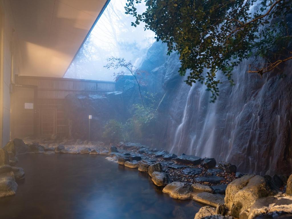 einen Fluss mit Felsen und einem Wasserfall in einem Gebäude in der Unterkunft Tabist Yabuki Golf Club in Yabuki