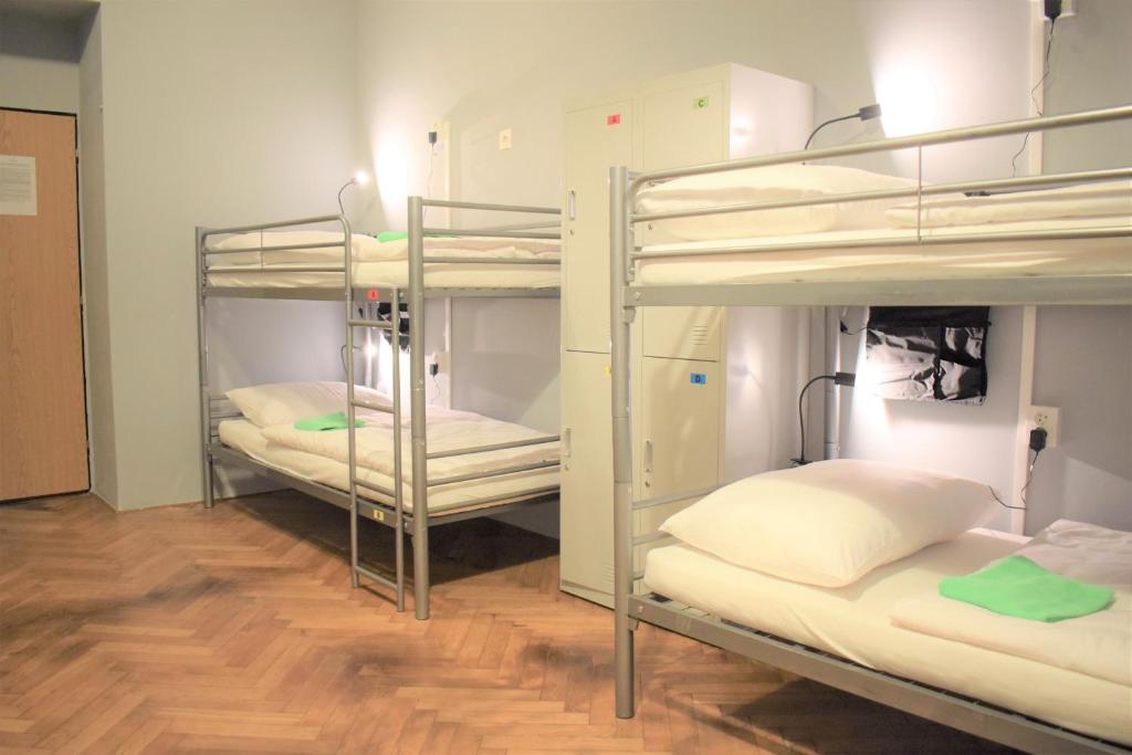 three bunk beds in a room with a wooden floor at GLOBE Hostel Prague ADULTS ONLY in Prague
