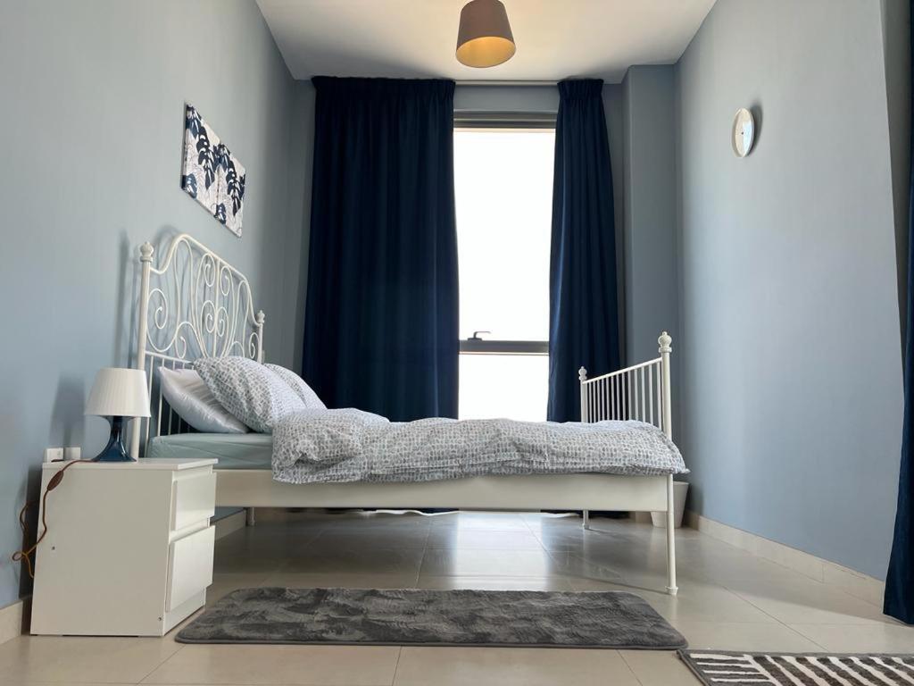 a bedroom with a bed with blue walls and a window at Cozy & Quiet Studio in Dubai