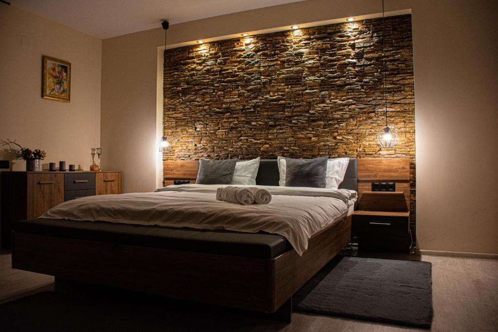 Un dormitorio con una pared de ladrillo y una cama grande en JANINE GARDEN, en Brasov