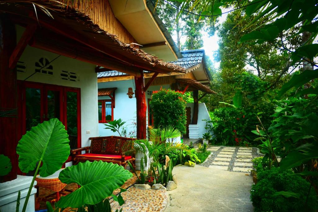 a house with a red bench in a garden at Sumatra Orangutan Discovery Villa in Bukit Lawang