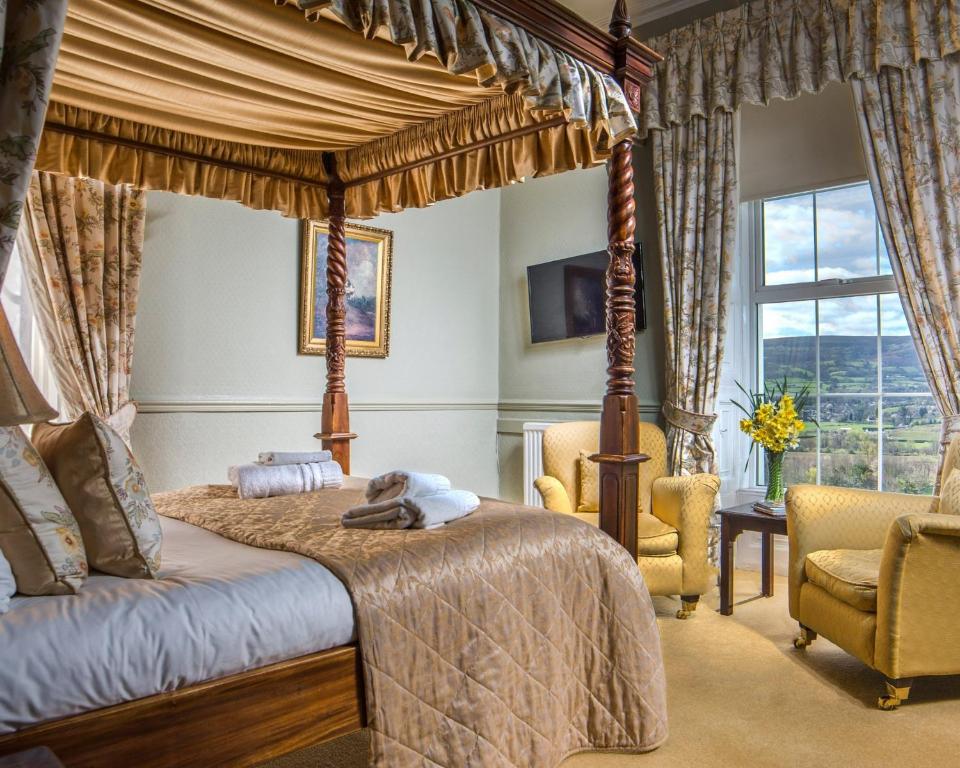 a bedroom with a canopy bed and two chairs at The Manor Hotel in Crickhowell