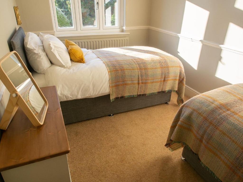 een slaapkamer met 2 bedden en een tafel met een spiegel bij The Beeches - Chatsworth Apartment No 1 - Sleeps 4 in Baslow