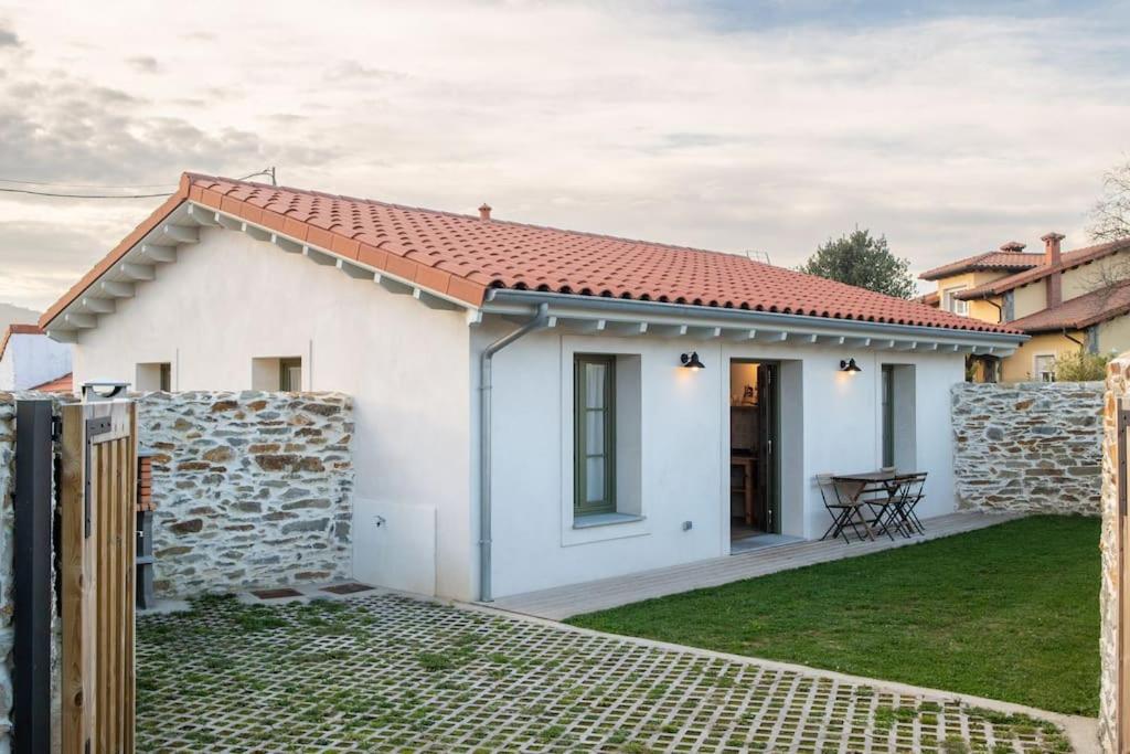 een klein wit huis met een stenen muur bij Casa Rural Monte Zarro in Cudillero