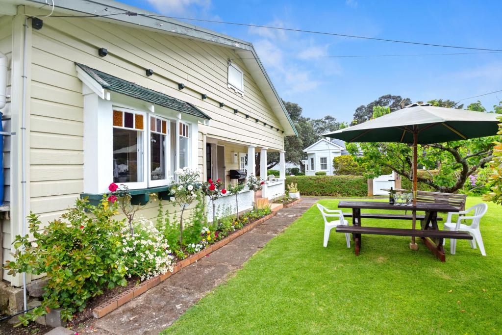 泰晤士的住宿－Whare Nui on Rennie - Thames Holiday Home，一个带桌子和遮阳伞的庭院