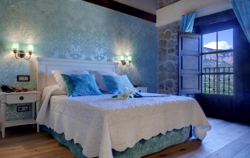 een slaapkamer met een bed met blauwe muren en een raam bij Hotel Boutique Real Posada De Liena in Murillo de Gállego