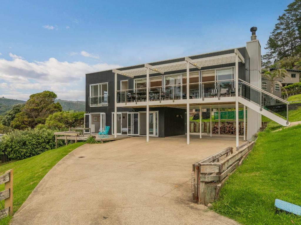 a large house with a large patio in front of it at Black House Lookout - Kuaotunu Holiday Home in Kuaotunu