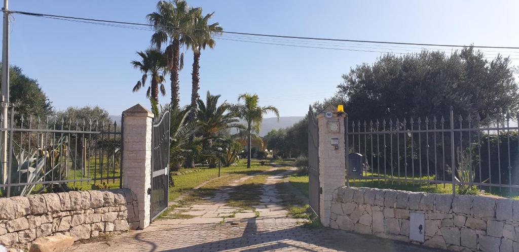 un ingresso a un cancello con una recinzione e una palma di Bellona 319 a Comiso