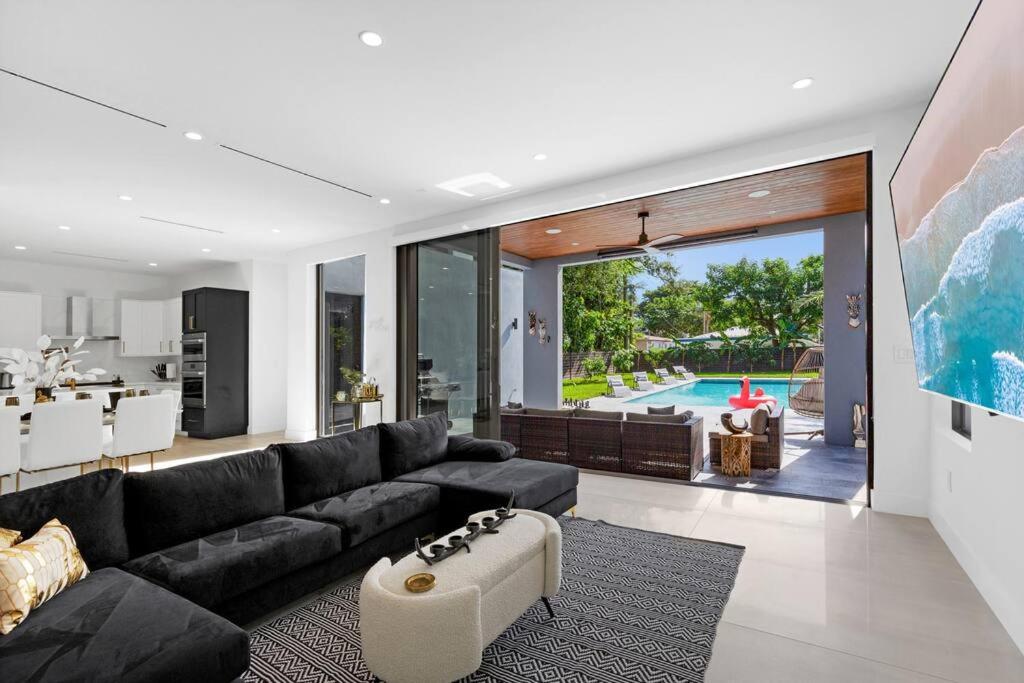 a living room with a black couch and a kitchen at Modern Villa w/ Resort Amenities & Salt Water Pool in Miami