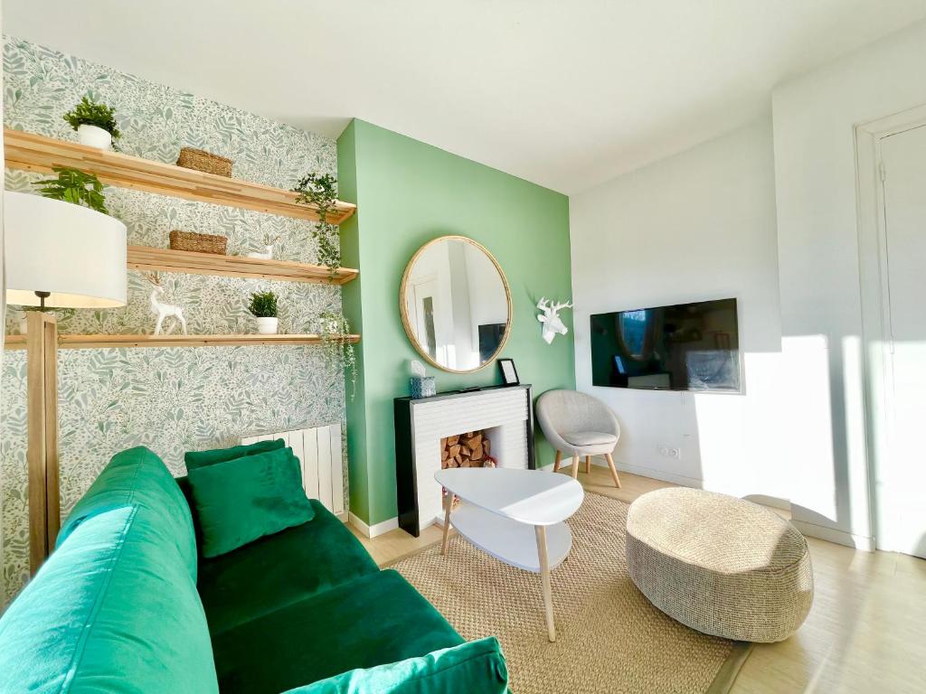 a living room with a green couch and a mirror at SMILE APPARTS - Appartements - Au coeur de Lorient - Au calme - Tout Confort in Lorient