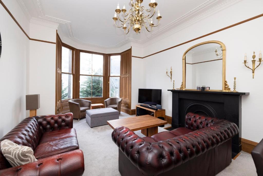 sala de estar con muebles de cuero y chimenea en ALTIDO 5 Bedroom Apt near Meadows and George Square en Edimburgo